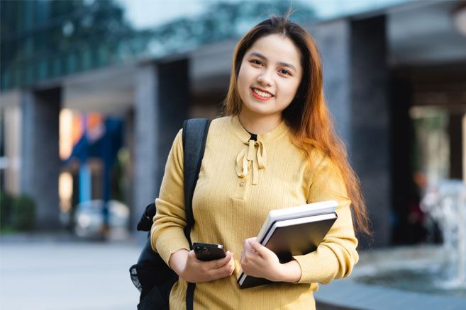 Female student outside holding books