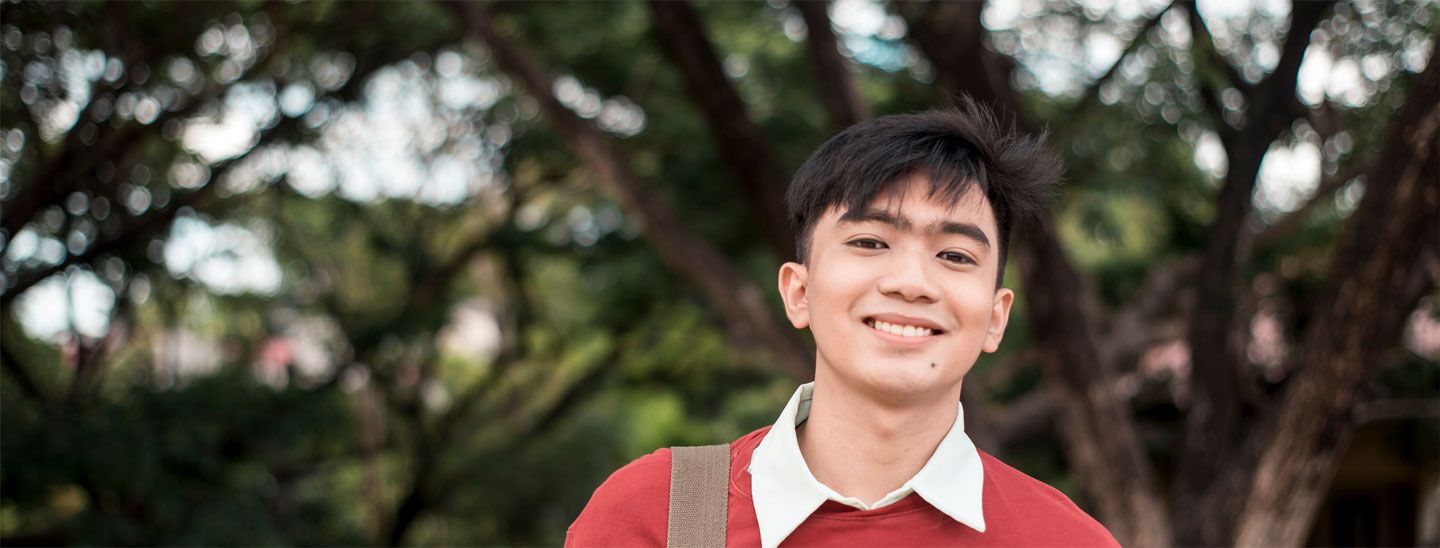 Male student standing outside red sweater