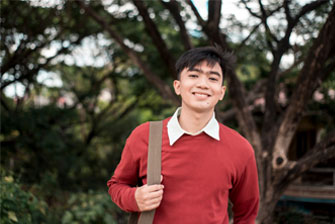 Male student standing outside red sweater